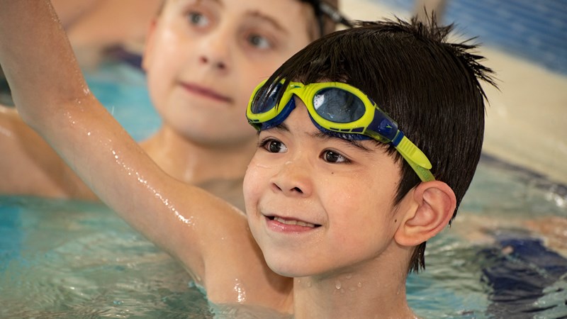A young boy in a swimming pool wearing goggles