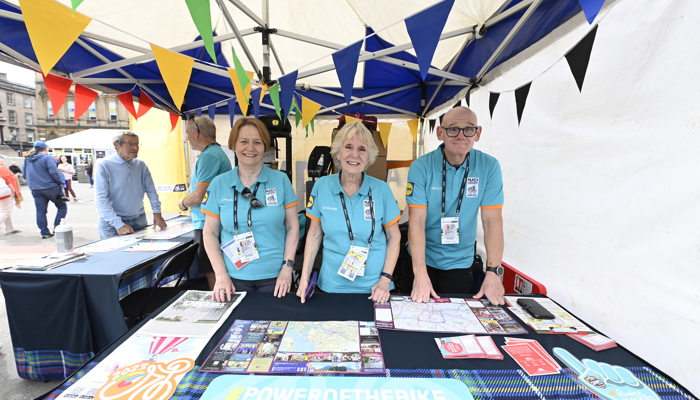 Three volunteers standing in a tent at the George Square fan zone during the 2023 UCI Cycling World Championships.