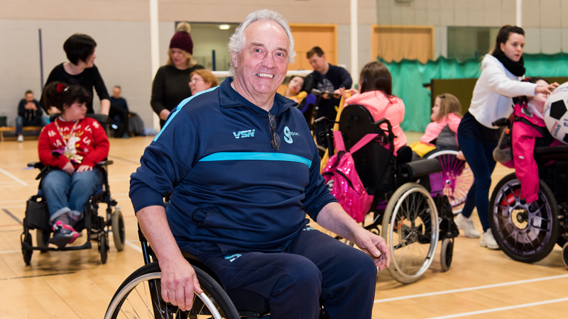 Wheelchair user and volunteer Michael McEleny smiling as he helps other young wheelchair users during a disability sport session.