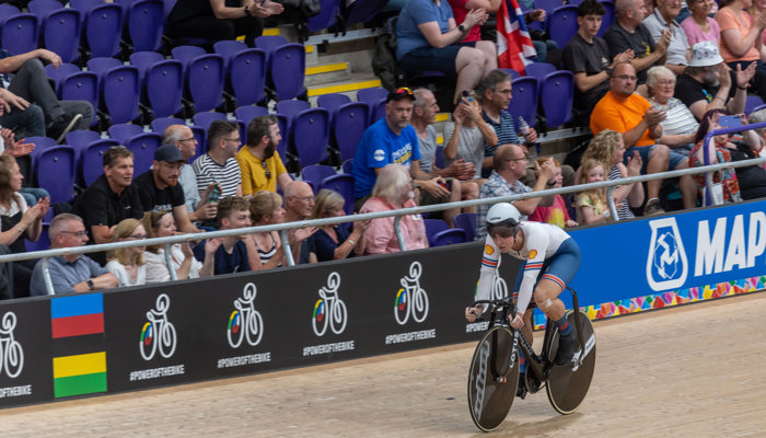 Spectators in the stands looking on as a track cyclist wearing lycra and helmet rides past during the 2023 UCI Cycling World Championships at the Sir Chris Hoy Velodrome.