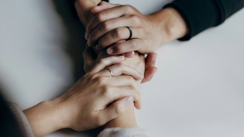 A close up of a group of three people hands, holding each others hands