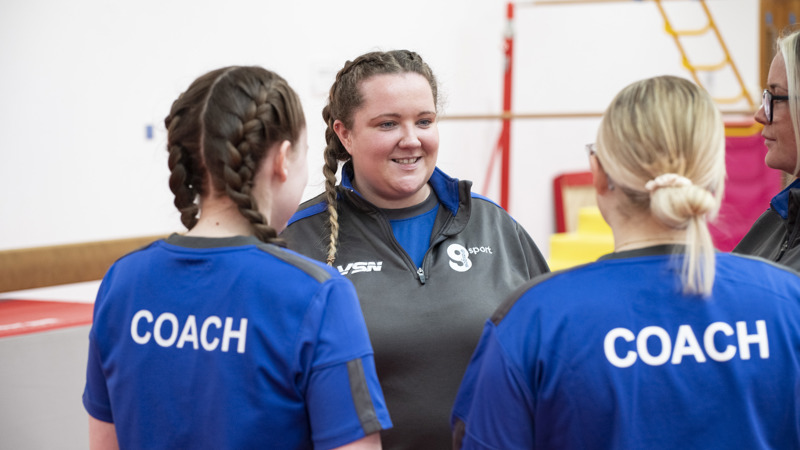 Three gymnastics coaches speaking to each other