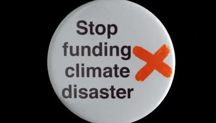 photo of a plastic badge bearing the words "stop funding climate disaster"