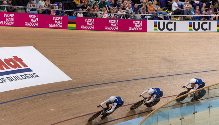 Three cyclist from the same team on the inside lane of the track at the Sir Chris Hoy Velodrome during the 2023 UCI Cycling World Championships.