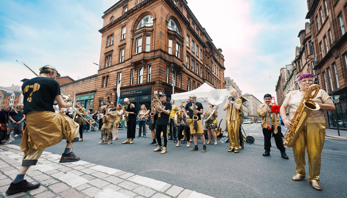 A brass band dressed in gold performs on a street