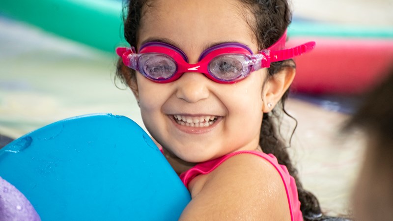 young girl at a swimming pool wearing goggles