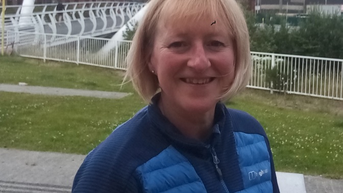 Person outside smiling with a bridge in the background