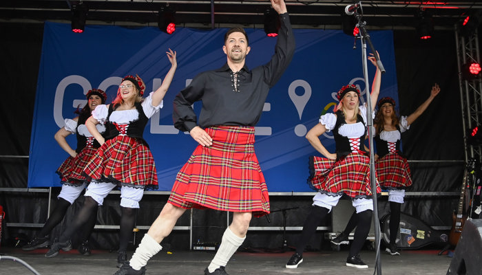 Scottish dancers performing at a GO LIVE event in Tollcross during the 2023 UCI Cycling World Championships. All the performers are wearing red tartan kilts.