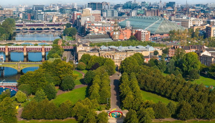 An aerial view over Glasgow Green, the Big G sculpture and the River Clyde.