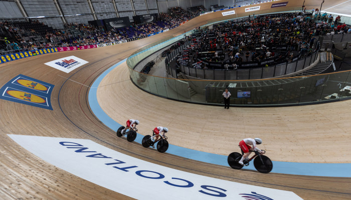 A wider shot of the Sir Chris Hoy Velodrome during the 2023 UCI Cycling World Championships, featuring three cyclists who are riding in a line.