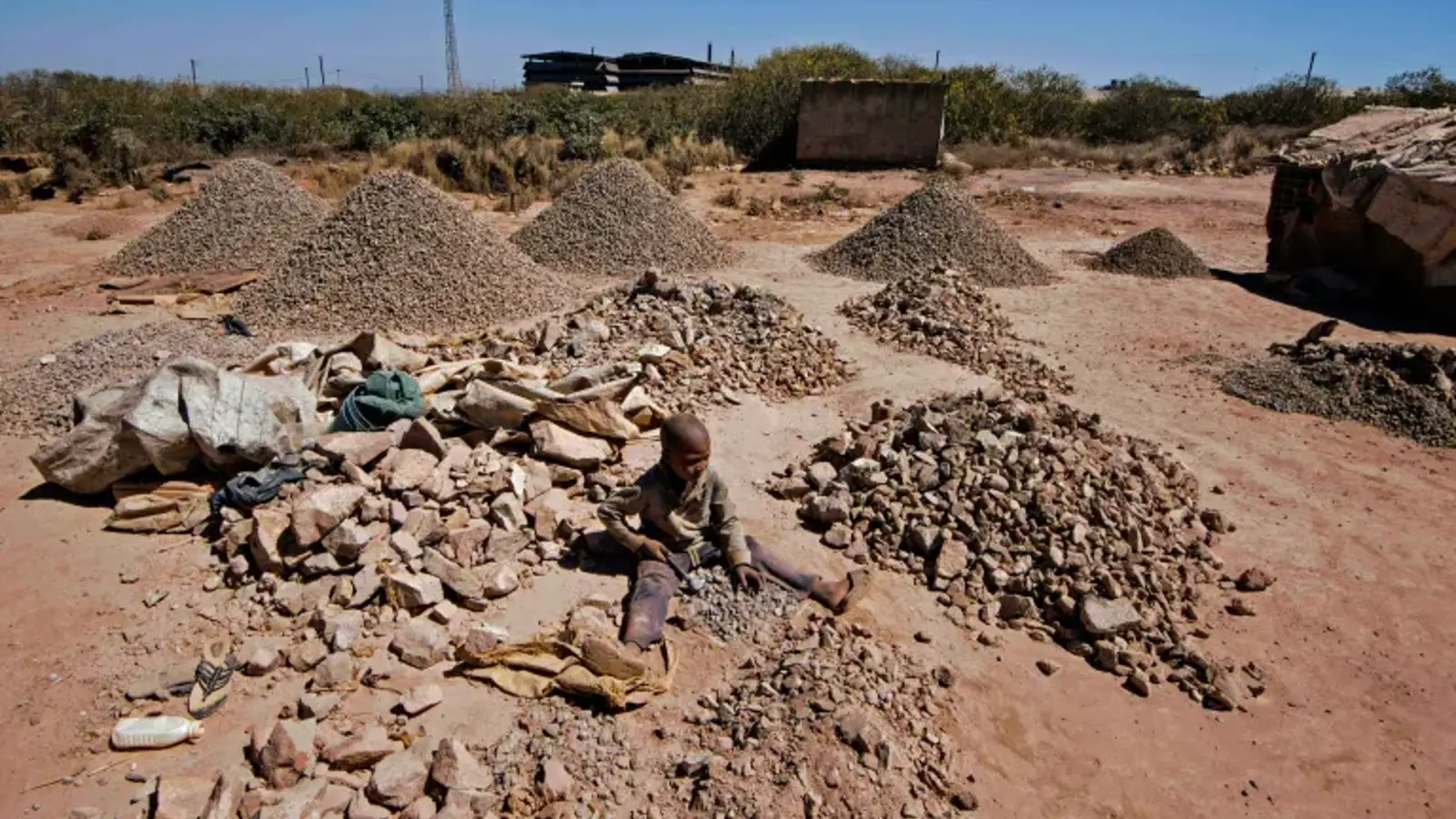 A photo of a child breaking rocks extracted from cobalt mining at a copper mine quarry and cobalt pit