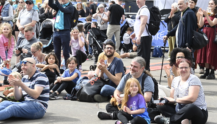 Crowds of people,  representing different ages, ethnicities and genders, in the George Square fan zone during the 2023 UCI Cycling World Championships.