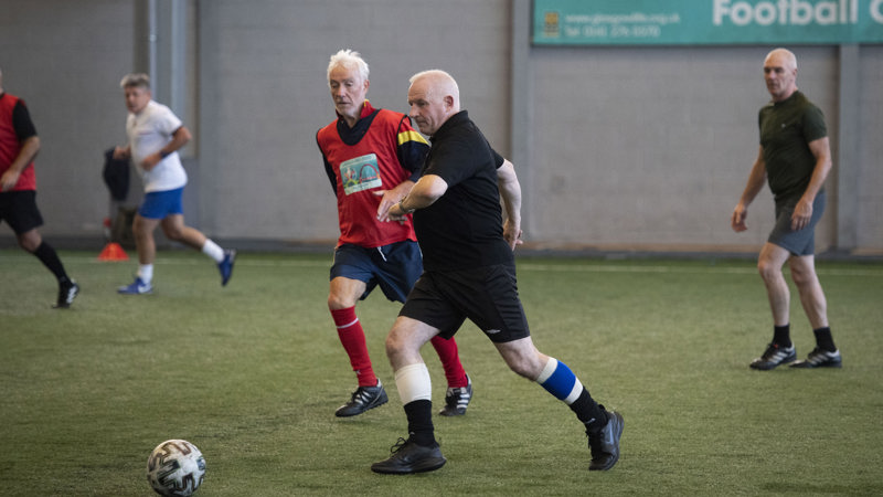 Group of men on an indoor football pitch playing walking football